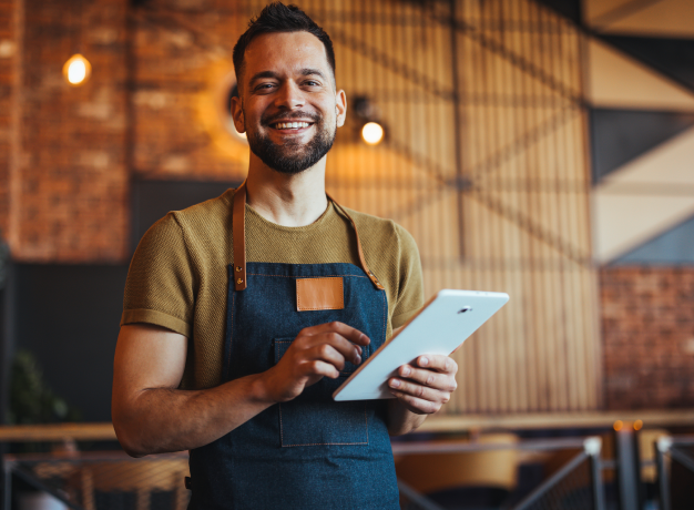 Smiling employee in an apron using a digital tablet for digital training.